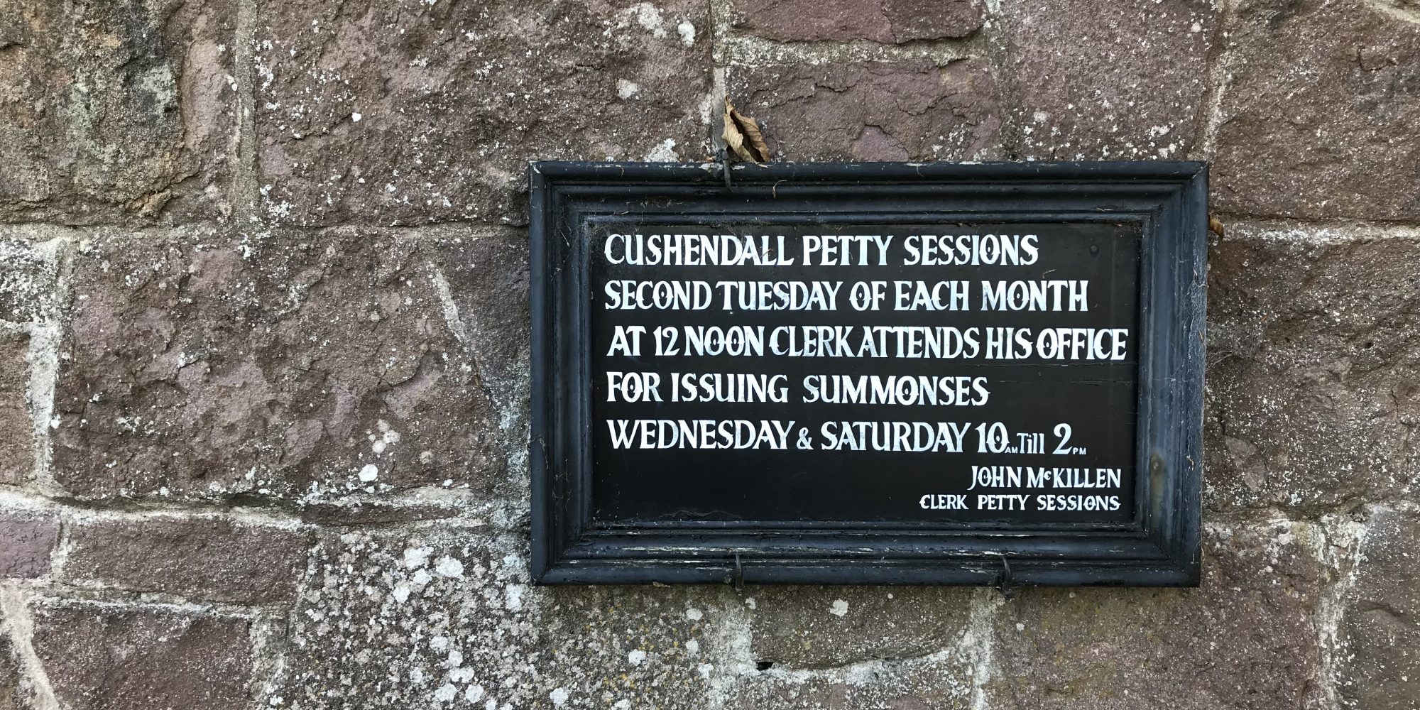 Vintage signage, framed in black wooden frame displayed on a stone wall at Ulster Folk Museum - National Museums of Northern Ireland.