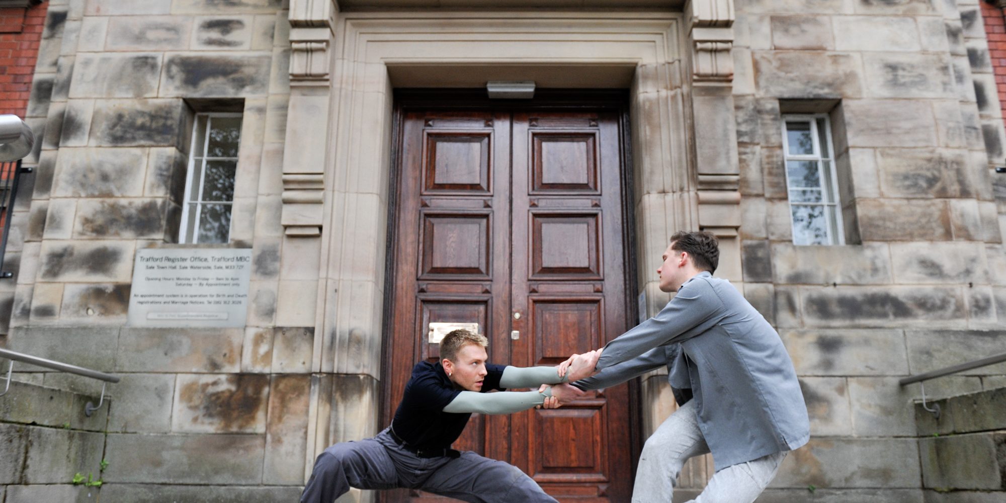 Two men performing alternative dance in front of a building