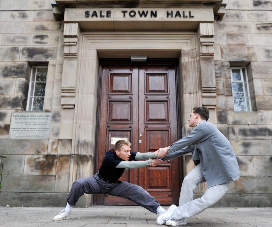 Two men performing alternative dance in front of a building